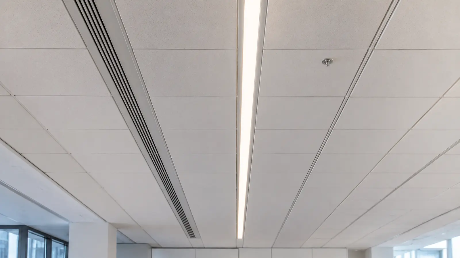 Recessed linear lighting integrated with technical service zones in an acoustic ceiling